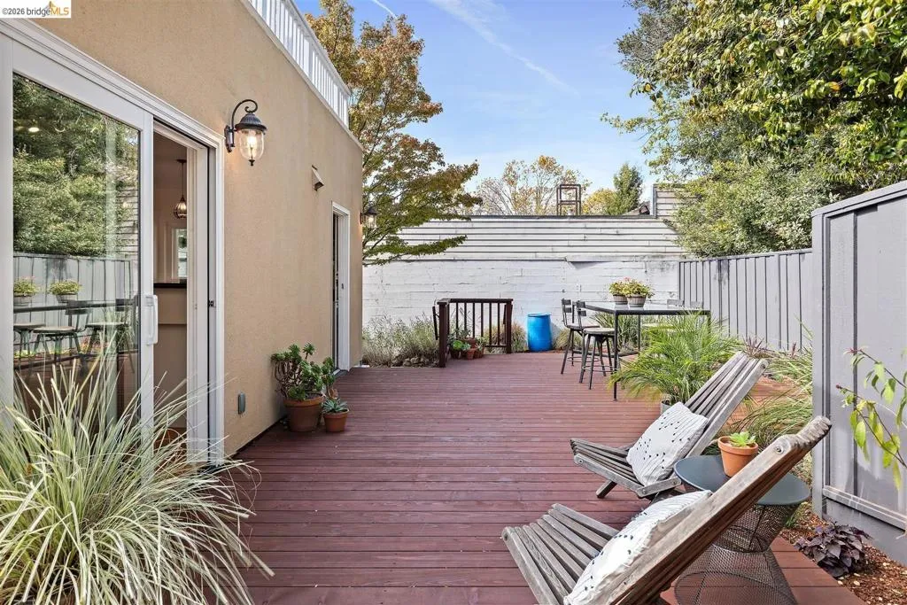 Expansive outdoor deck with rich wood-finish flooring, featuring a stucco exterior with an outdoor wall sconce Expansive outdoor deck with rich wood-finish flooring, featuring a stucco exterior with an outdoor wall sconce