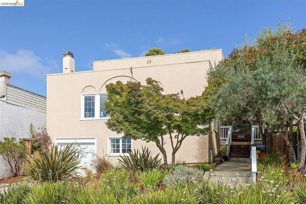 Stucco exterior with arched architectural details, white-framed windows, an integrated garage, and a concrete pathway leading to the entry Stucco exterior with arched architectural details, white-framed windows, an integrated garage, and a concrete pathway leading to the entry
