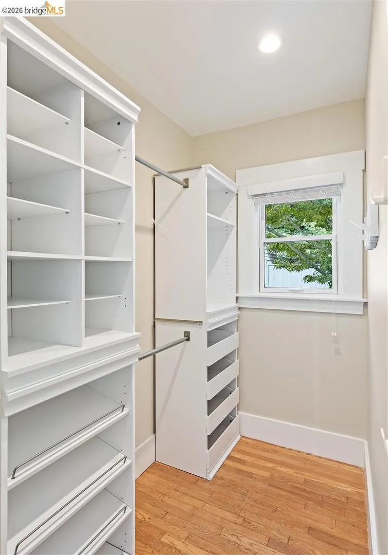 Walk-in closet with built-in shelving, integrated drawers, hanging rods, and a window Walk-in closet with built-in shelving, integrated drawers, hanging rods, and a window