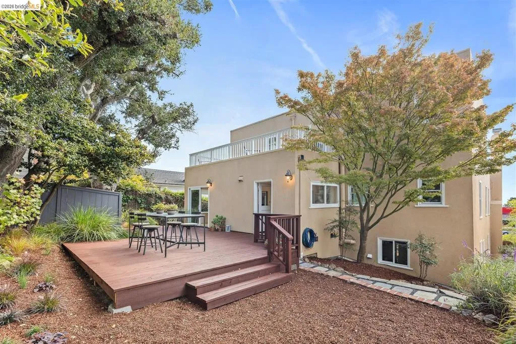 Exterior with a multi-level deck, stucco finish, upper-level balcony, mature trees, and landscaping Exterior with a multi-level deck, stucco finish, upper-level balcony, mature trees, and landscaping