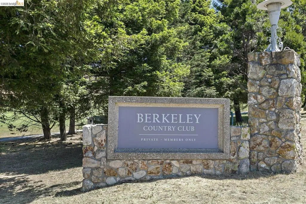 Stone-clad entrance sign with a decorative light fixture, surrounded by mature trees and natural landscaping Stone-clad entrance sign with a decorative light fixture, surrounded by mature trees and natural landscaping