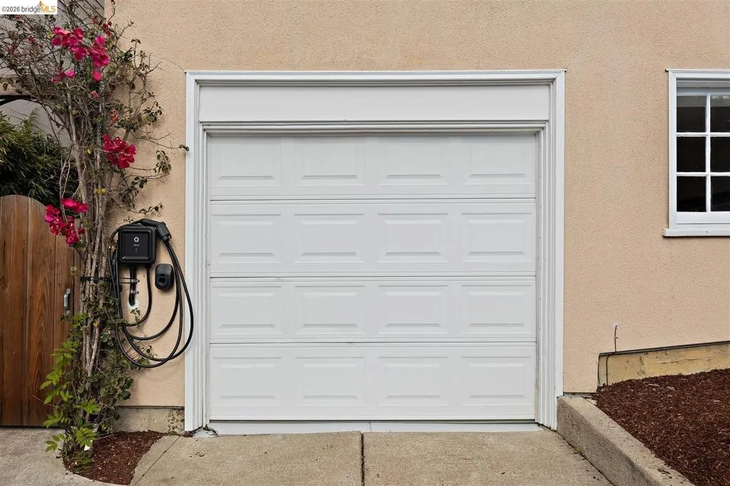 White panel garage door with decorative trim, stucco exterior, and multi-pane window White panel garage door with decorative trim, stucco exterior, and multi-pane window