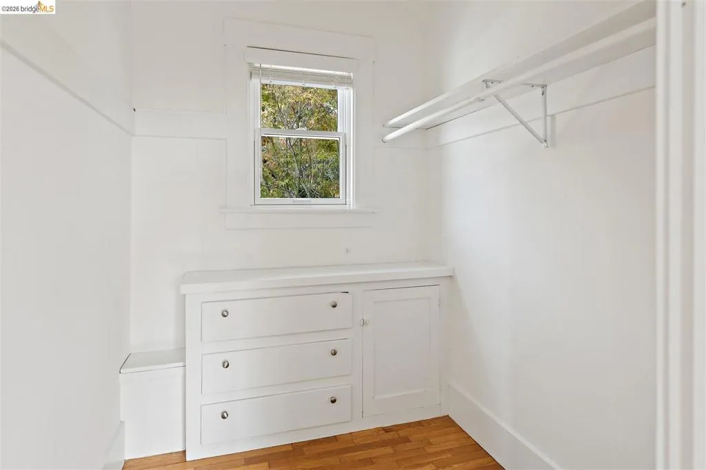 Built-in dresser with three drawers, integrated cabinet, window, and wood-finish flooring Built-in dresser with three drawers, integrated cabinet, window, and wood-finish flooring