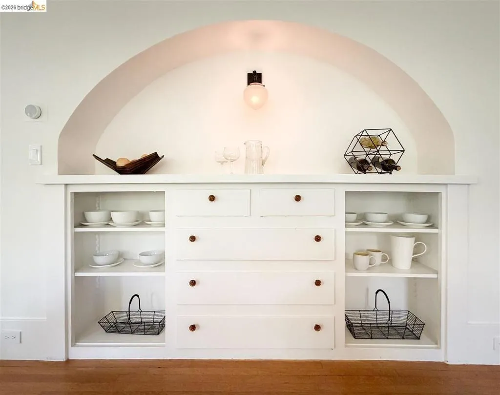 Built-in cabinetry with an arched alcove, integrated sconce lighting, open shelving, and drawer storage Built-in cabinetry with an arched alcove, integrated sconce lighting, open shelving, and drawer storage