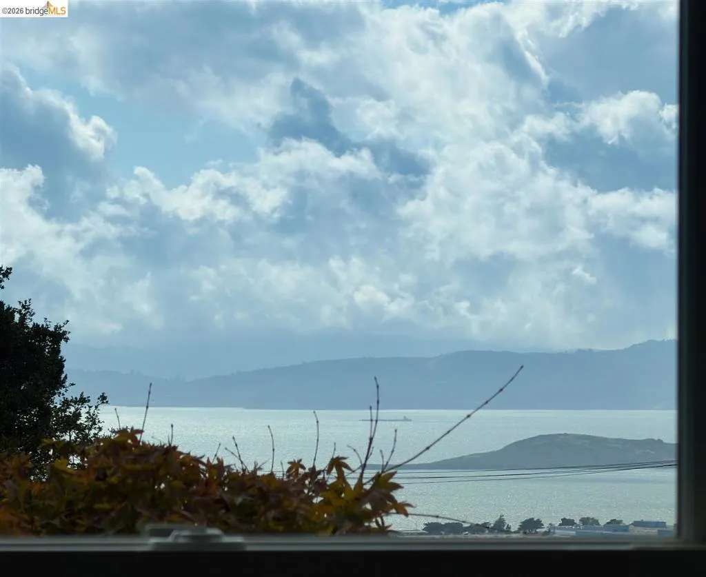 Expansive water scenery framed by a window, featuring distant hills and a partially visible landmass Expansive water scenery framed by a window, featuring distant hills and a partially visible landmass