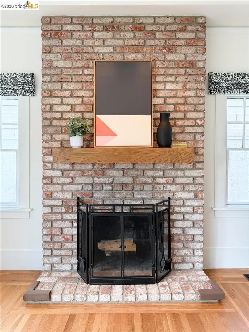 Exposed brick fireplace with a wood-finish mantel and a black metal fire screen Exposed brick fireplace with a wood-finish mantel and a black metal fire screen