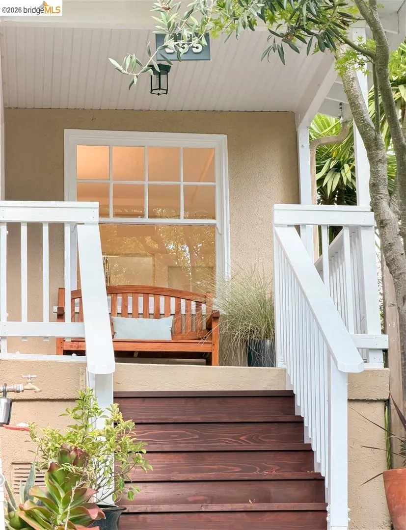 Wood-stained steps leading to a stucco exterior with white window trim, white porch railings, and a beadboard ceiling Wood-stained steps leading to a stucco exterior with white window trim, white porch railings, and a beadboard ceiling