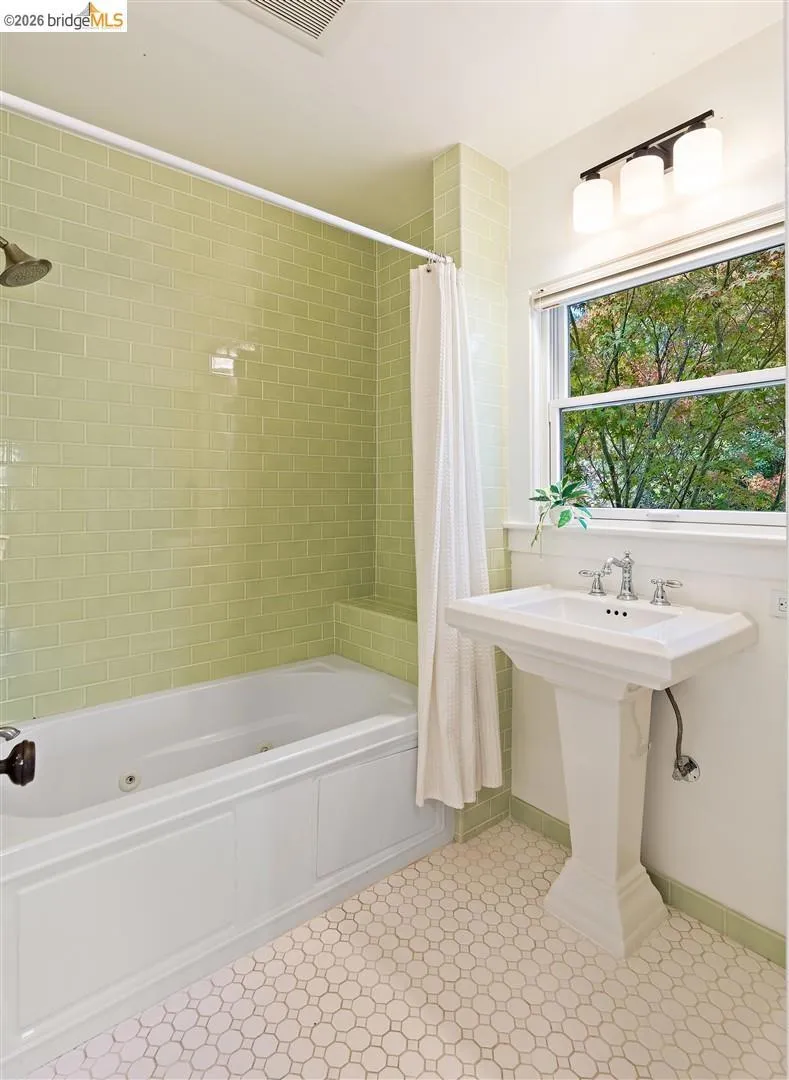 Pedestal sink with chrome fixtures, white soaking tub, green subway tile shower surround, and octagonal tile flooring Pedestal sink with chrome fixtures, white soaking tub, green subway tile shower surround, and octagonal tile flooring