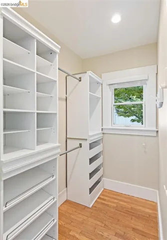 Walk-in closet with built-in shelving, integrated drawers, hanging rods, and a window