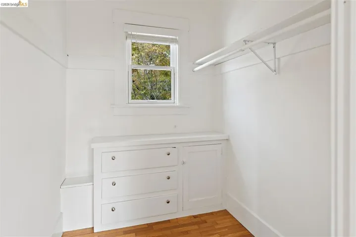 Built-in dresser with three drawers, integrated cabinet, window, and wood-finish flooring