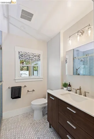 Vanity with wood-finish cabinetry, integrated sink, and brushed nickel hardware