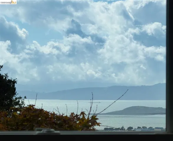 Expansive water scenery framed by a window, featuring distant hills and a partially visible landmass