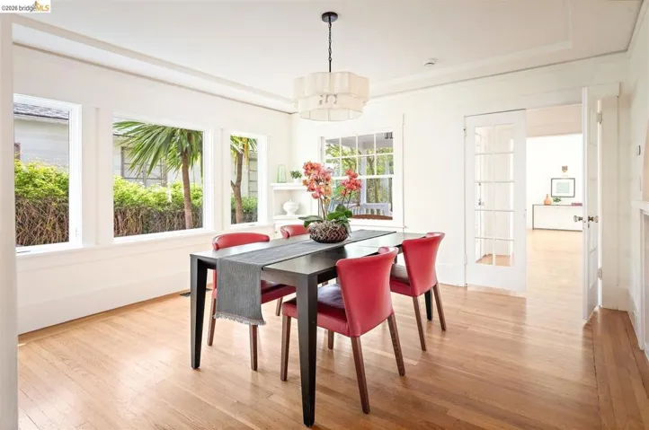 Hardwood flooring throughout, multiple large windows, tray ceiling detail, built-in shelving, and a glass-paneled door