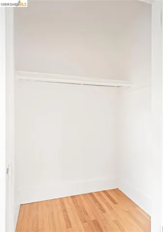 Closet space featuring wood-finish flooring and a built-in hanging rod