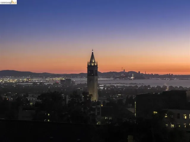 Skyline with a prominent illuminated tower, distant city lights, and expansive water body