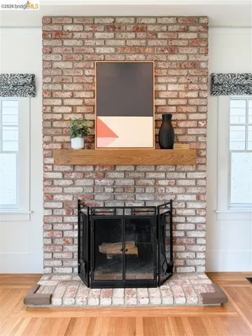 Exposed brick fireplace with a wood-finish mantel and a black metal fire screen