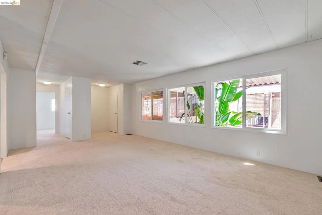 Empty room with plenty of natural light and light colored carpet