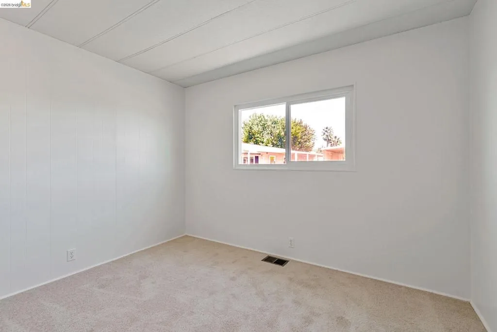 Spare room featuring carpet flooring and baseboards
