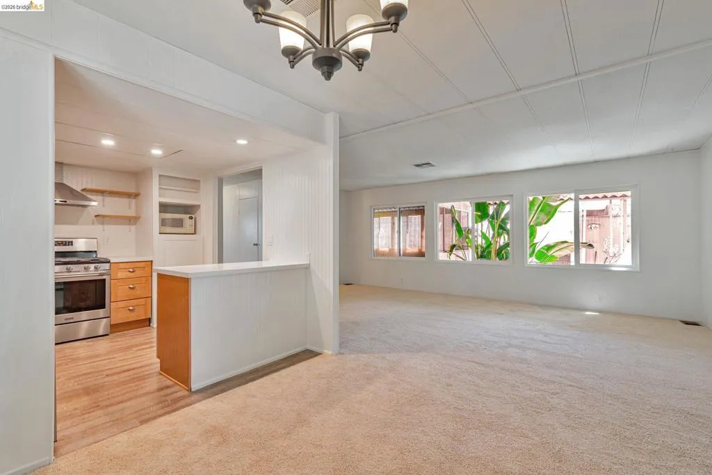 Kitchen featuring open shelves, gas stove, light countertops, light colored carpet, and open floor plan