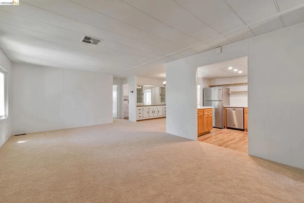 Unfurnished living room featuring light colored carpet and a decorative wall