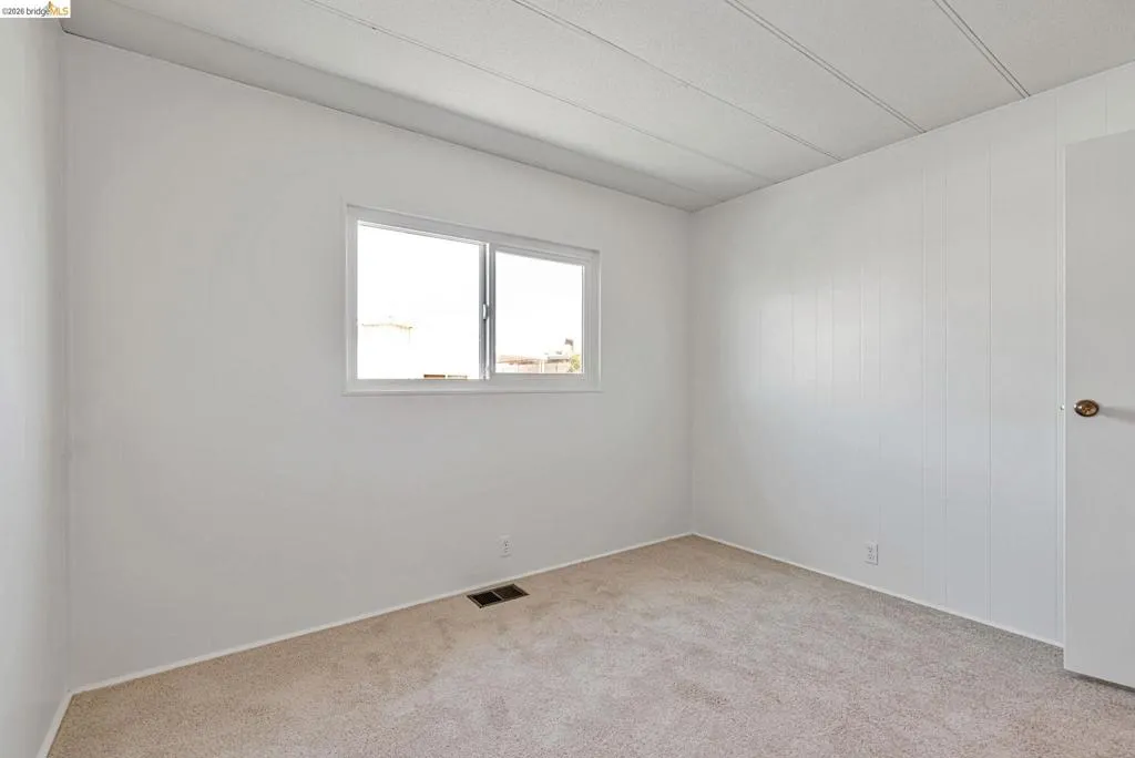 Unfurnished room featuring light carpet and baseboards