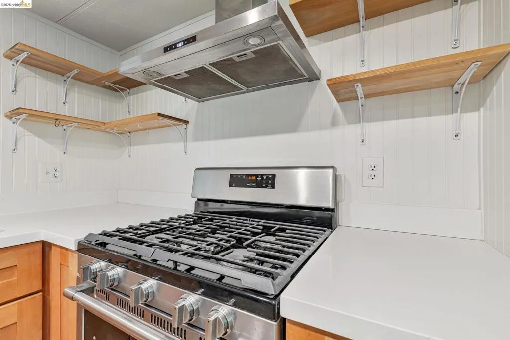 Kitchen with open shelves, gas range, and under cabinet range hood