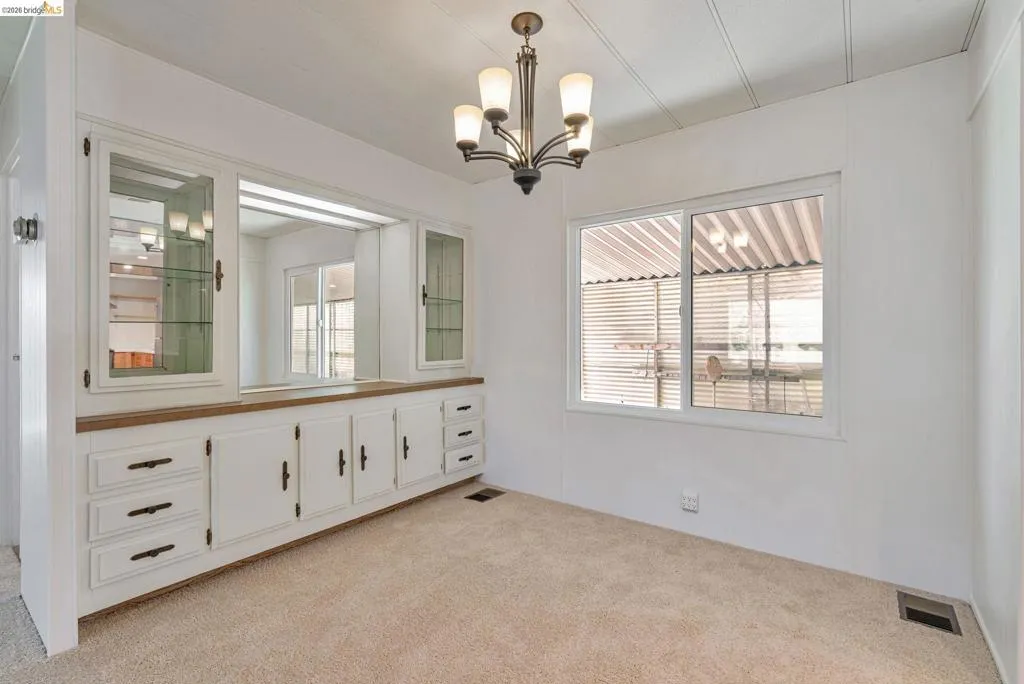 Spare room with light carpet and a chandelier