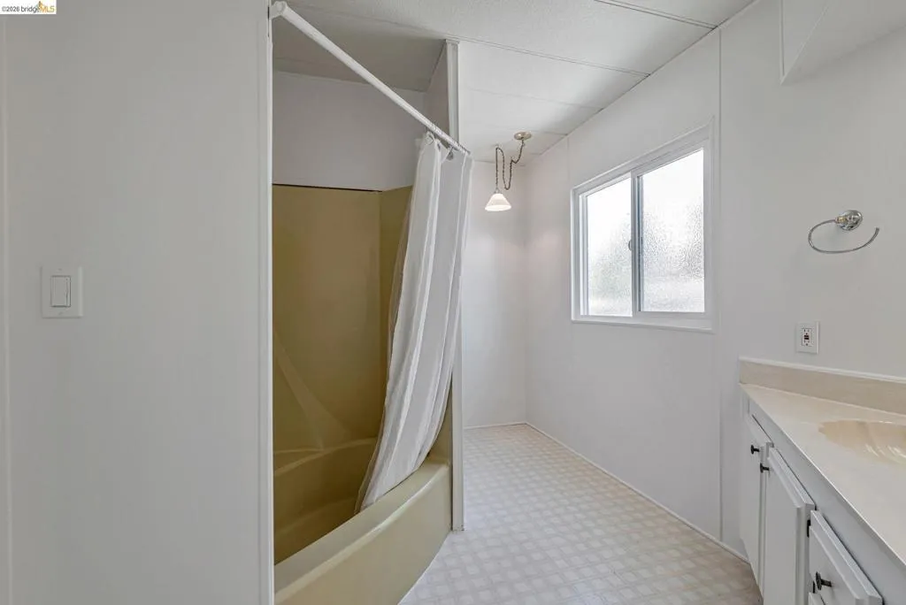 Full bath featuring vanity, shower / bathtub combination with curtain, and light flooring