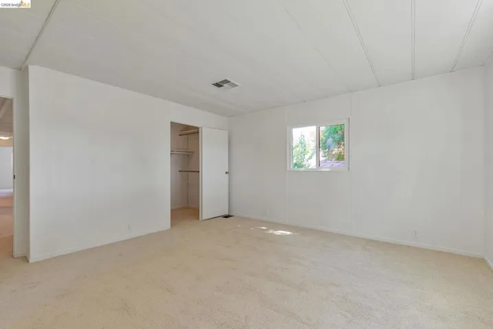 Unfurnished bedroom featuring a spacious closet and light carpet