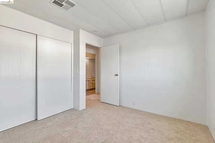 Unfurnished bedroom featuring light carpet and a closet