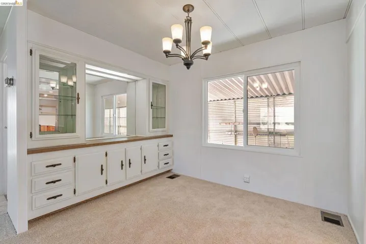 Spare room with light carpet and a chandelier