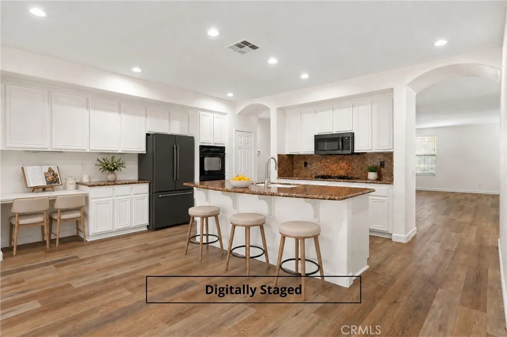 Chef's delight kitchen with statement island, breakfast bar, dual ovens, mounted microwave, granite countertops, and gas cooktop. Digitally staged image. Chef's delight kitchen with statement island, breakfast bar, dual ovens, mounted microwave, granite countertops, and gas cooktop. Digitally staged image.