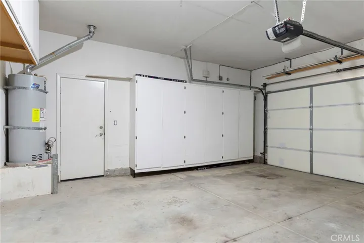 Direct access garage has storage cabinets and roll up door