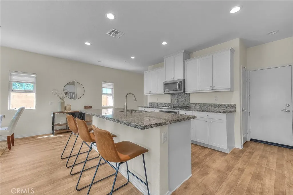 Modern kitchen showcases crisp white cabinetry, granite countertops, and a spacious island.
