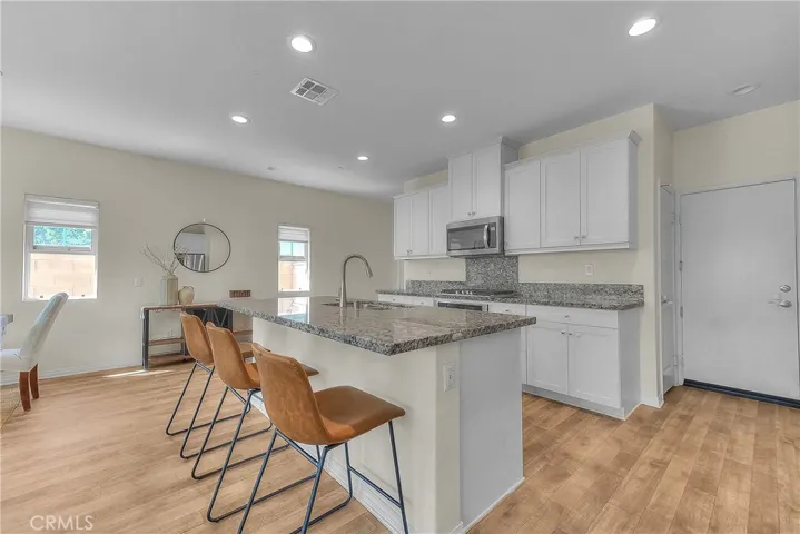 Modern kitchen showcases crisp white cabinetry, granite countertops, and a spacious island.