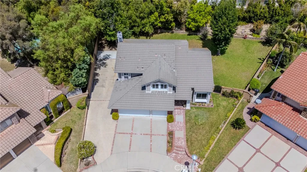 Aerial view with a closer look at the front of the home with the huge gated RV parking to the left and the sprawling pool-sized side yard to the right.