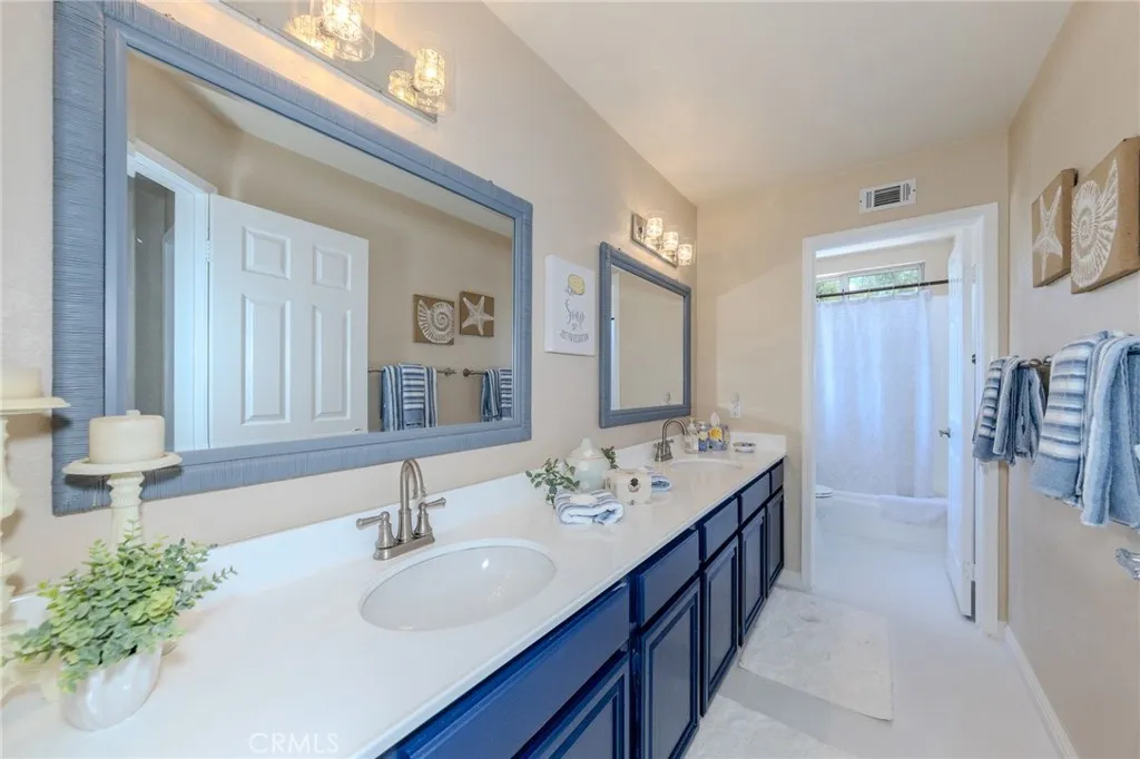 Secondary bedrooms share this full hall bath with double vanity and privacy door to commode and tub/shower room.