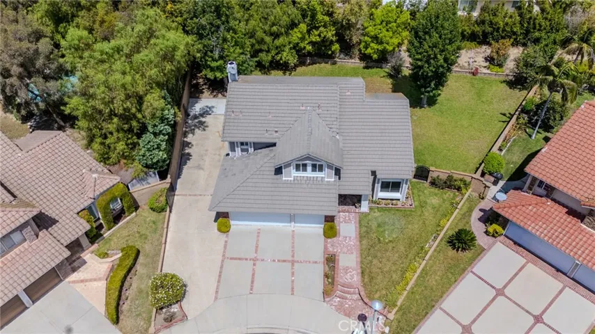 Aerial view with a closer look at the front of the home with the huge gated RV parking to the left and the sprawling pool-sized side yard to the right.
