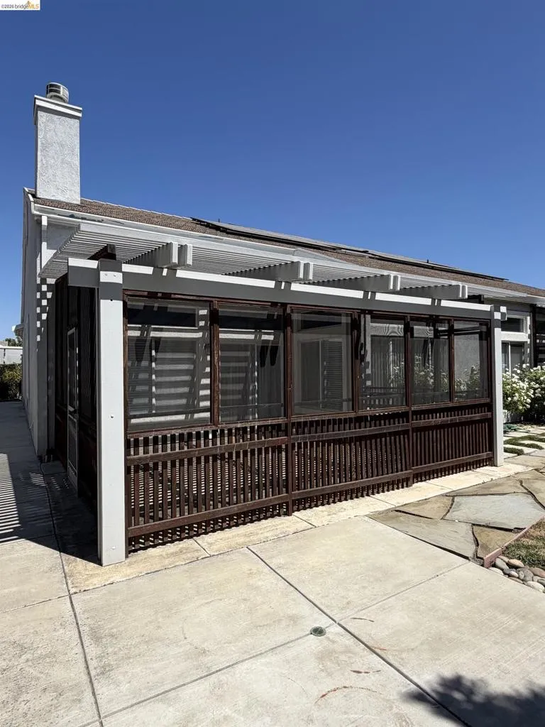 Screened-in patio with horizontal slatted shade covering and dark wood-finish railing