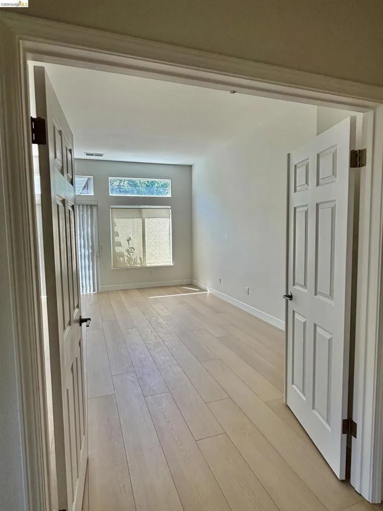 Expansive room with high ceilings, wood-finish flooring, multiple windows, and panel doors