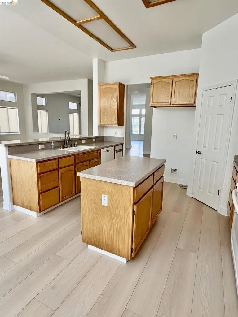 Kitchen featuring a central island, light wood-finish cabinetry, and stone-look countertops