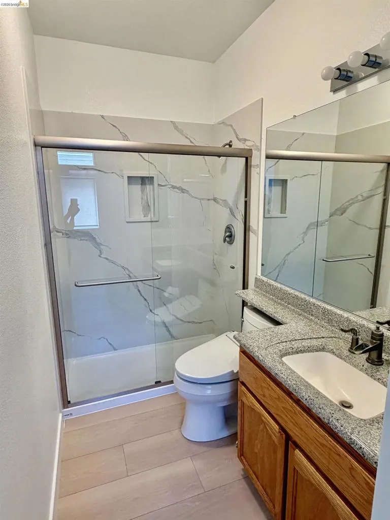 Shower with sliding glass enclosure and tiled surround featuring a built-in niche
