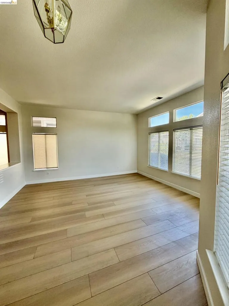 Wood-finish flooring, multiple windows, and a geometric pendant light fixture