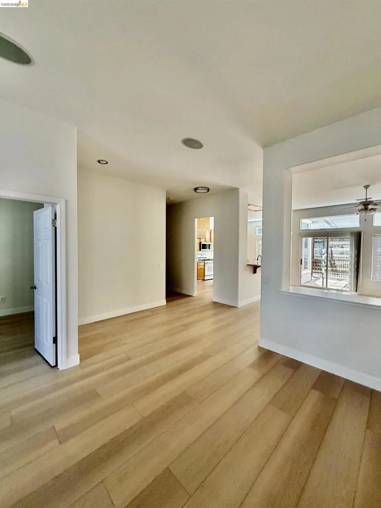 Wood-finish flooring throughout, recessed ceiling lighting, and a white interior door