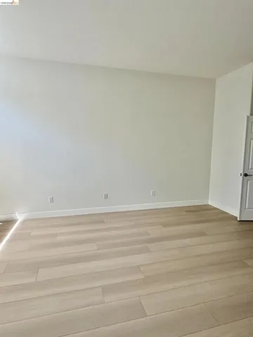 Neutral wall color, light wood-finish flooring, and a white interior door