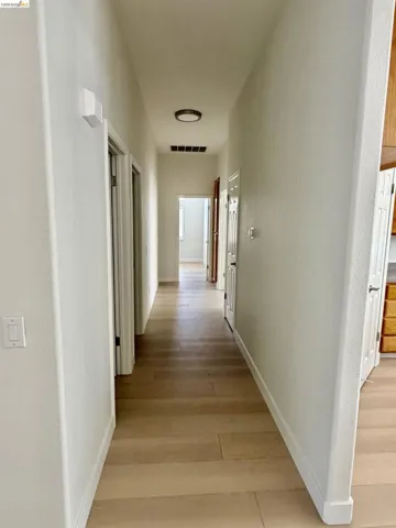 Hallway featuring wood-finish flooring, recessed ceiling light fixtures, and white painted walls