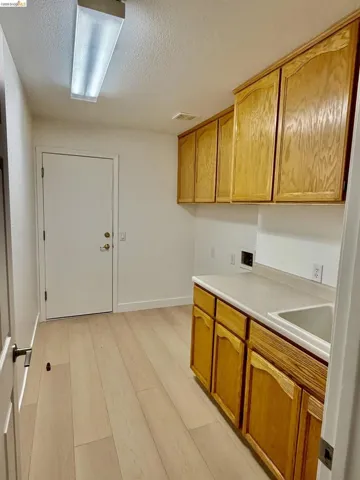 Wood-finish flooring, ample cabinetry, integrated sink, and white countertops