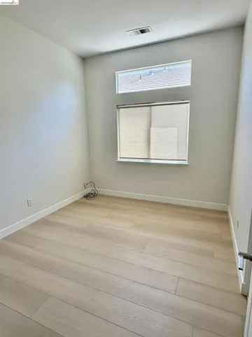 Light wood-finish flooring, white walls, and a window with blinds