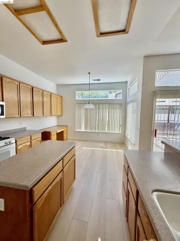 Recessed ceiling panels, wood-finish cabinetry, light-toned countertops, contemporary pendant lighting, and plank-style flooring