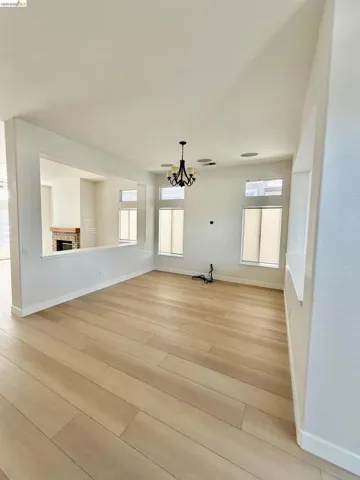 Spacious room featuring light wood-finish flooring, a decorative chandelier, recessed lighting, and multiple windows with blinds